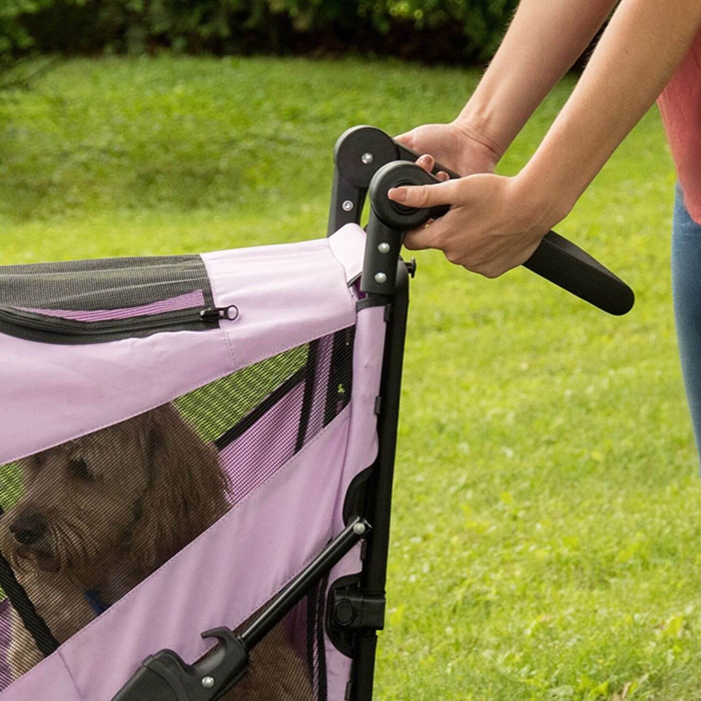 Person pressing the button on the adjustable handle for the Pet Gear Excursion dog stroller.