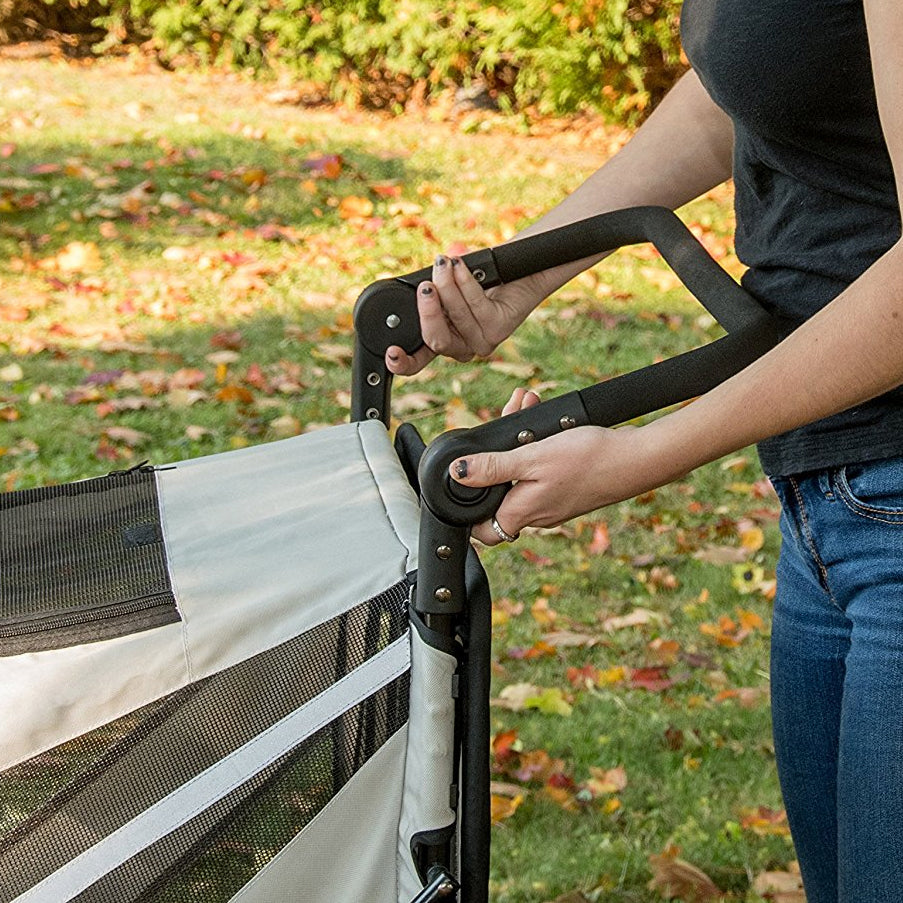 Person pressing the button to adjust handle on the Pet Gear Expedition dog stroller.