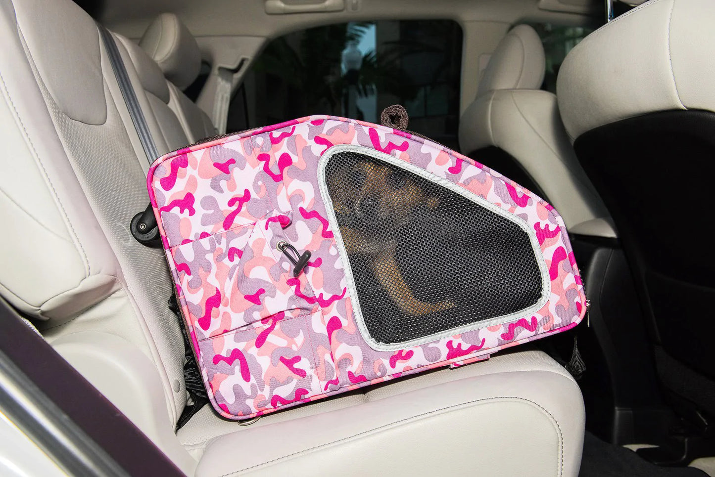 Small dog sitting inside a car in a Petique pet carrier car seat for dogs.