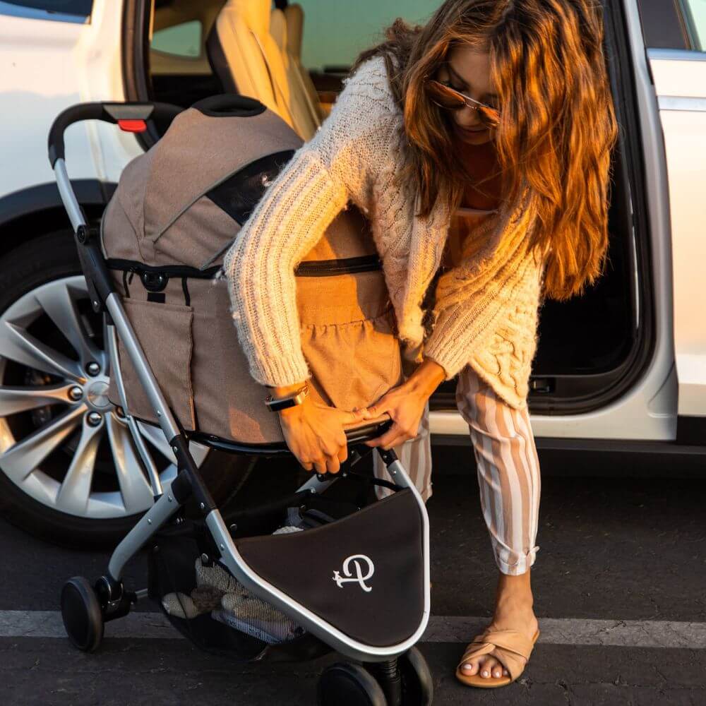 Woman removing the detachable Petique Newport pet carrier from the dog stroller to place inside her car.